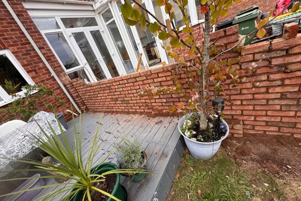 a brick patio with a tree and potted plants
